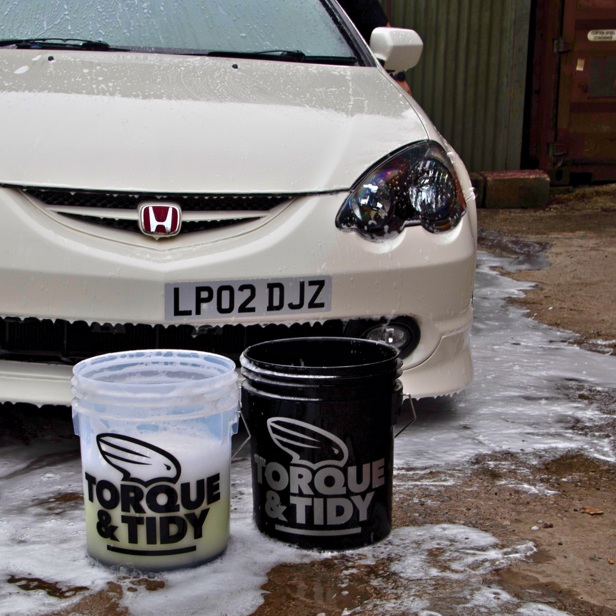 Translucent and black Torque & Tidy wash buckets in front of a Honda