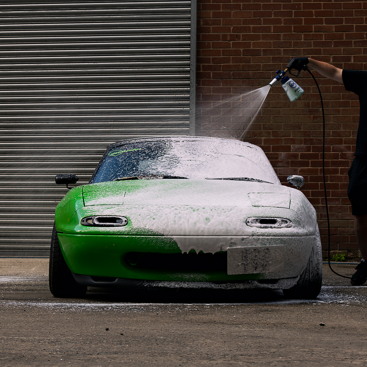 Spraying The Snow onto a green car with a snow foam lance