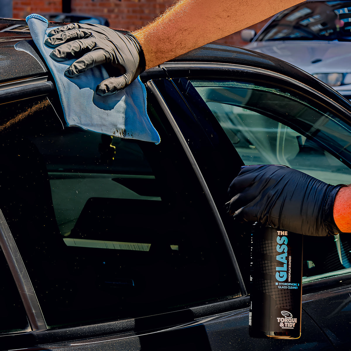 Wiping a car window with The Glass Cloth and The Glass spray