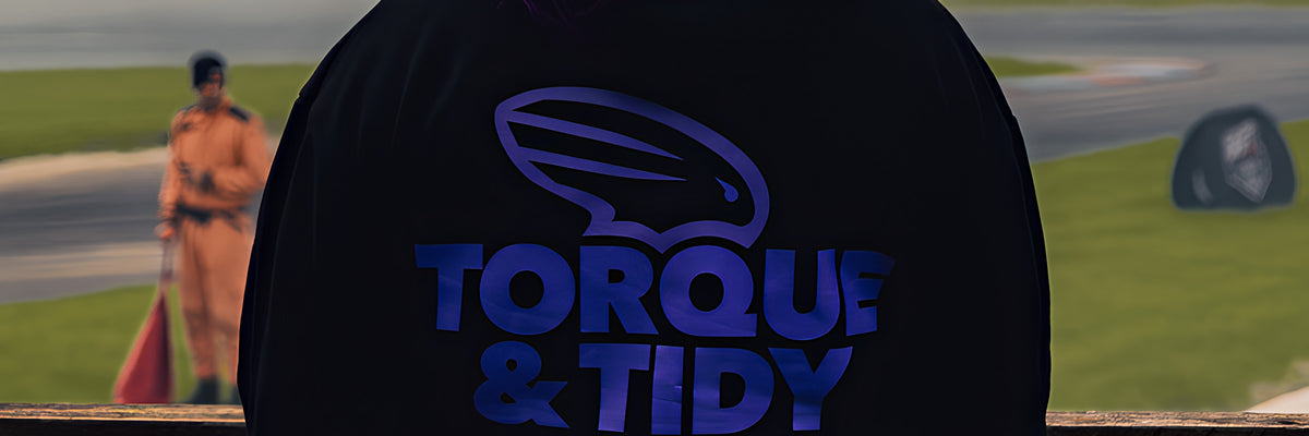 The purple Torque & Tidy logo on the back of a hoodie at the track fence