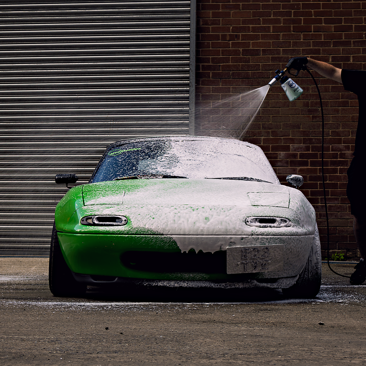 Spraying The Snow onto a green car with a snow foam lance