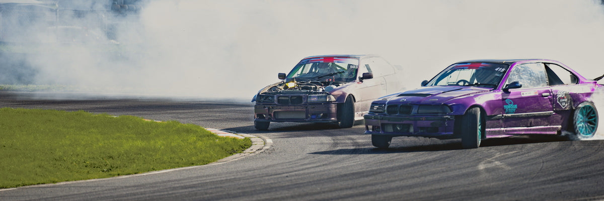 Two drift cars side by side through a corner in tyre smoke at a Drift League GB event
