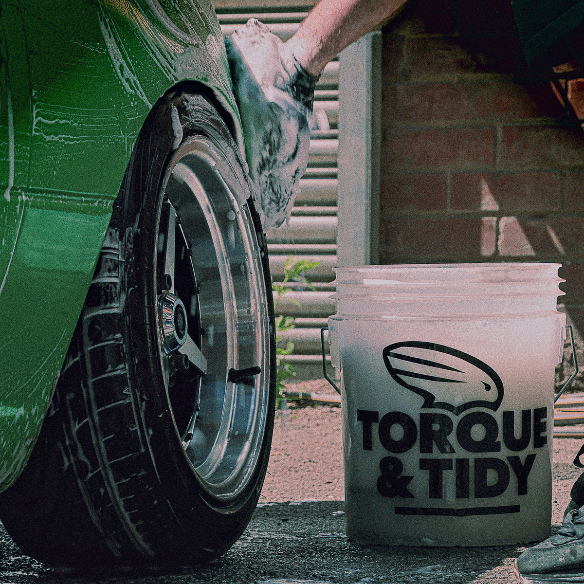 Torque & Tidy wash bucket beside a wheel during a wash