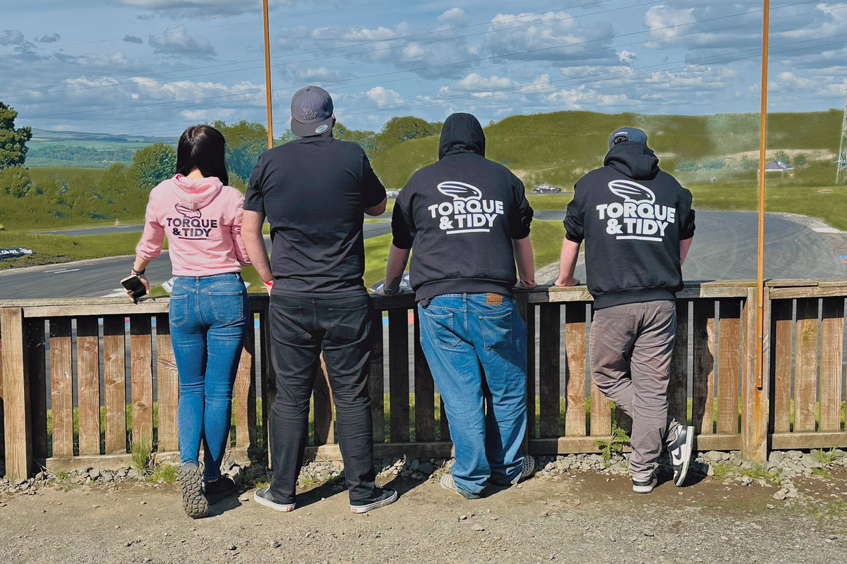 Four of the crew at the fence over the drift track in Torque & Tidy hoodies and tees