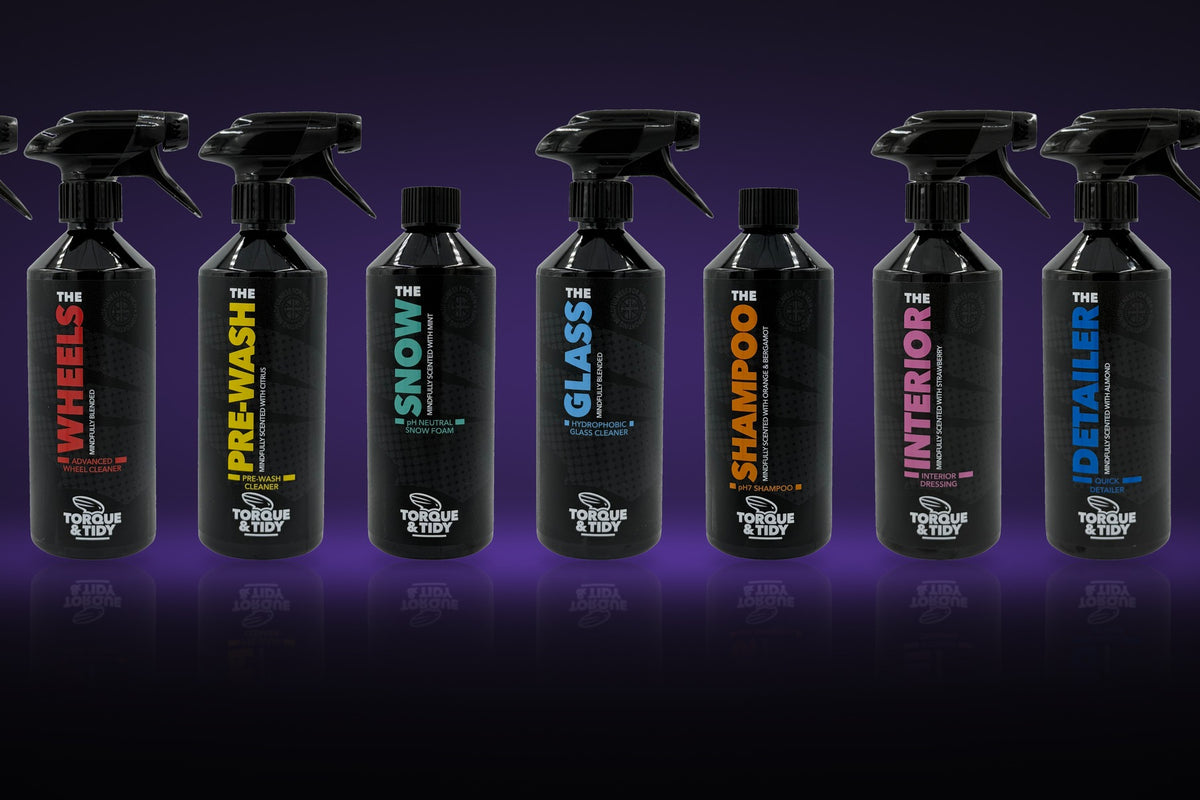 The Torque & Tidy range of car care bottles in a row on a dark purple background